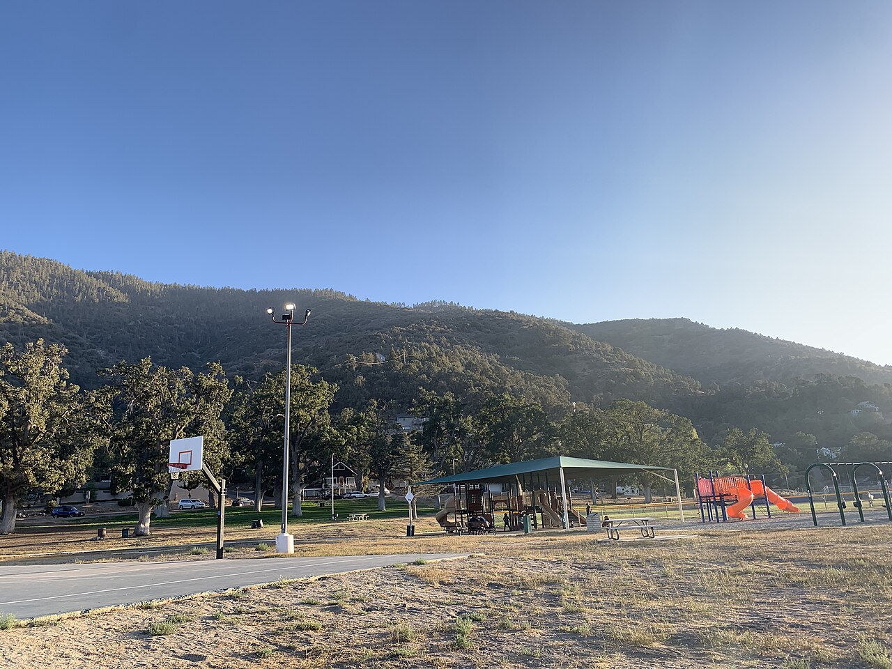 Picnic shelter, playground and basketball court at Frazier Mountain Park beneath wooded hills.